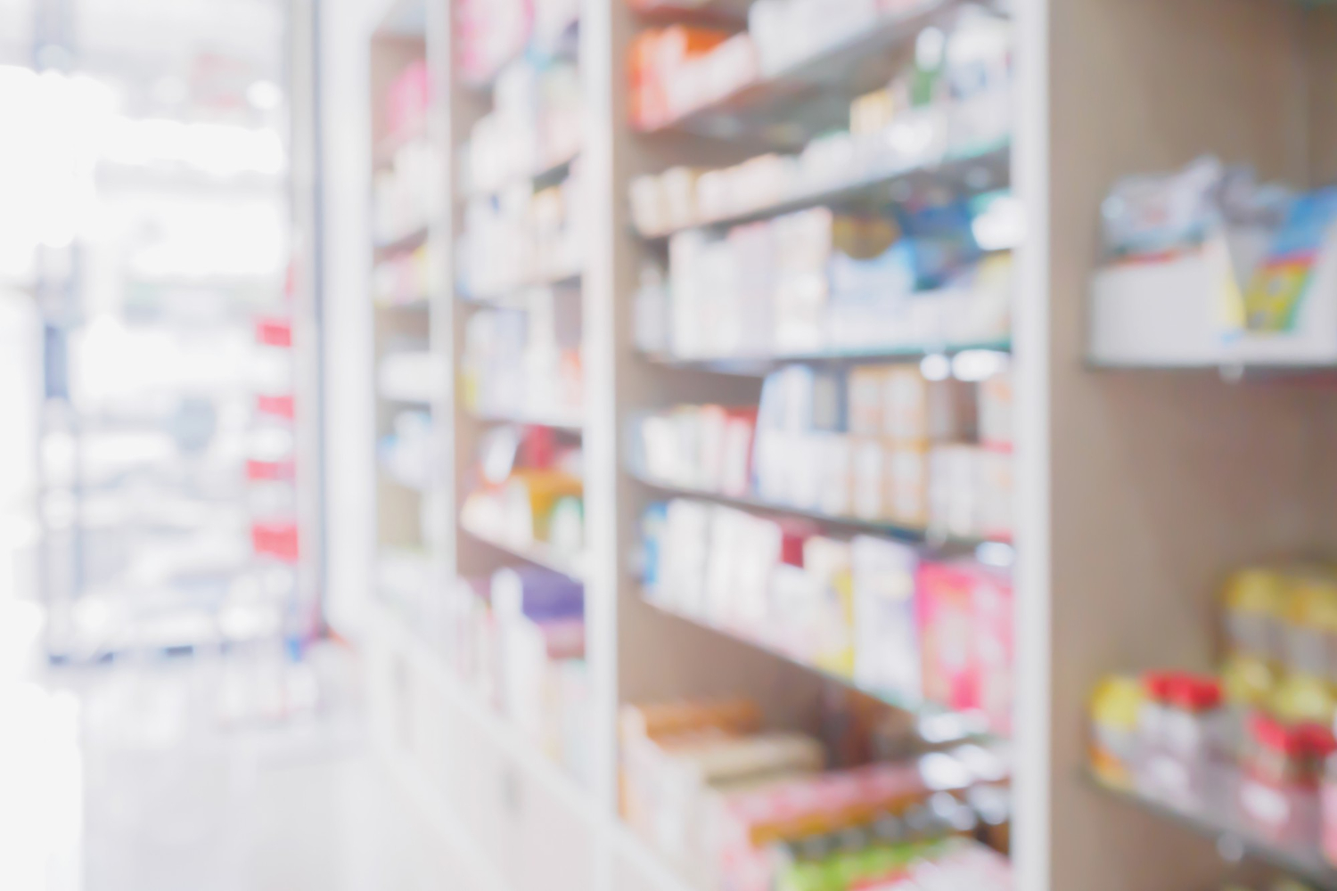 2366 Blurry image of shelves stocked with various products in a brightly lit store or pharmacy.